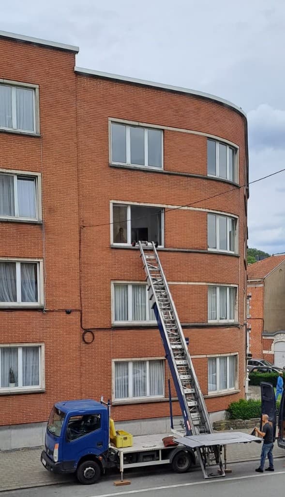 Opérateur et camion lift devant un immeuble en briques